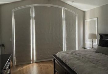 West Hollywood bedroom featuring closed custom Roman shades on large arched windows and French doors, effectively blocking daylight.