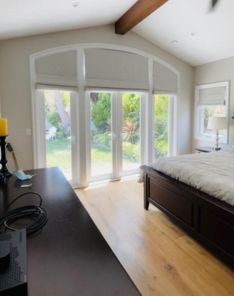 Bright West Hollywood bedroom showcasing Roman shades partially raised to reveal natural garden views.