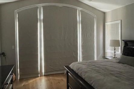 West Hollywood bedroom featuring closed custom Roman shades on large arched windows and French doors, effectively blocking daylight.